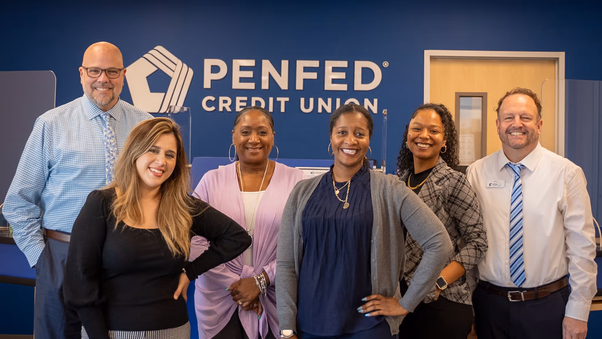 Diverse group of PenFed workers smiling for the camera in the office