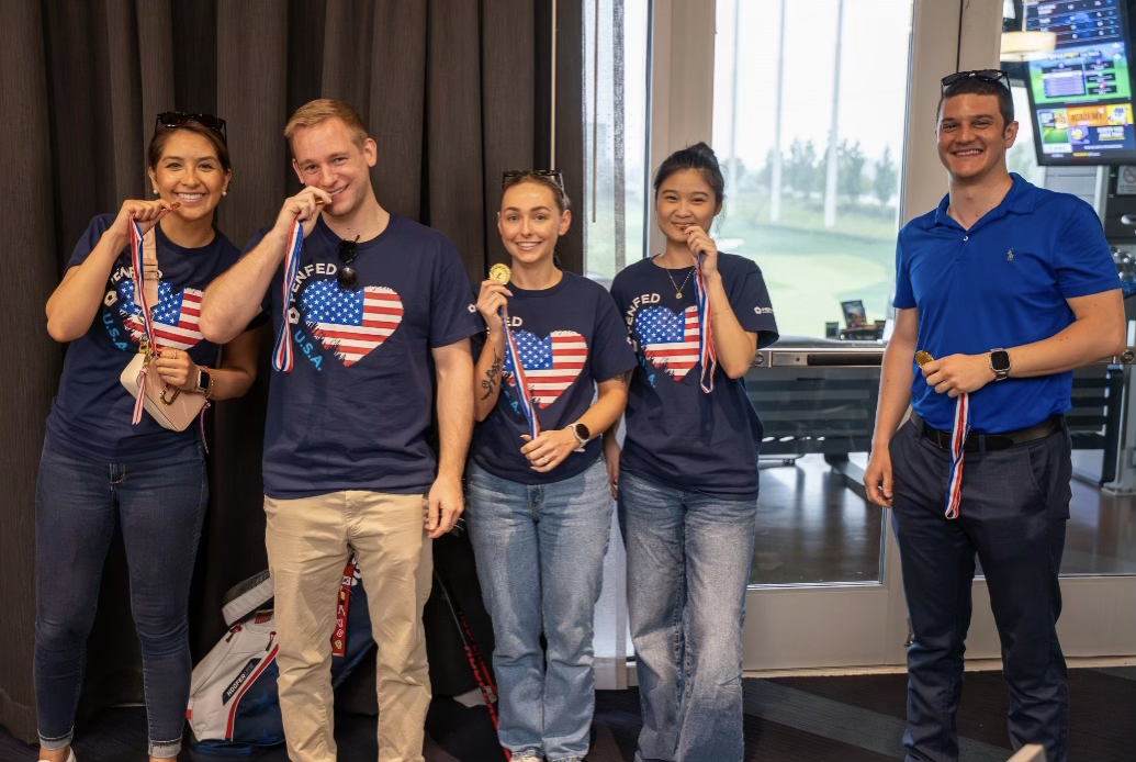Group of three PenFed workers volunteering at a community event standing at their organization's table