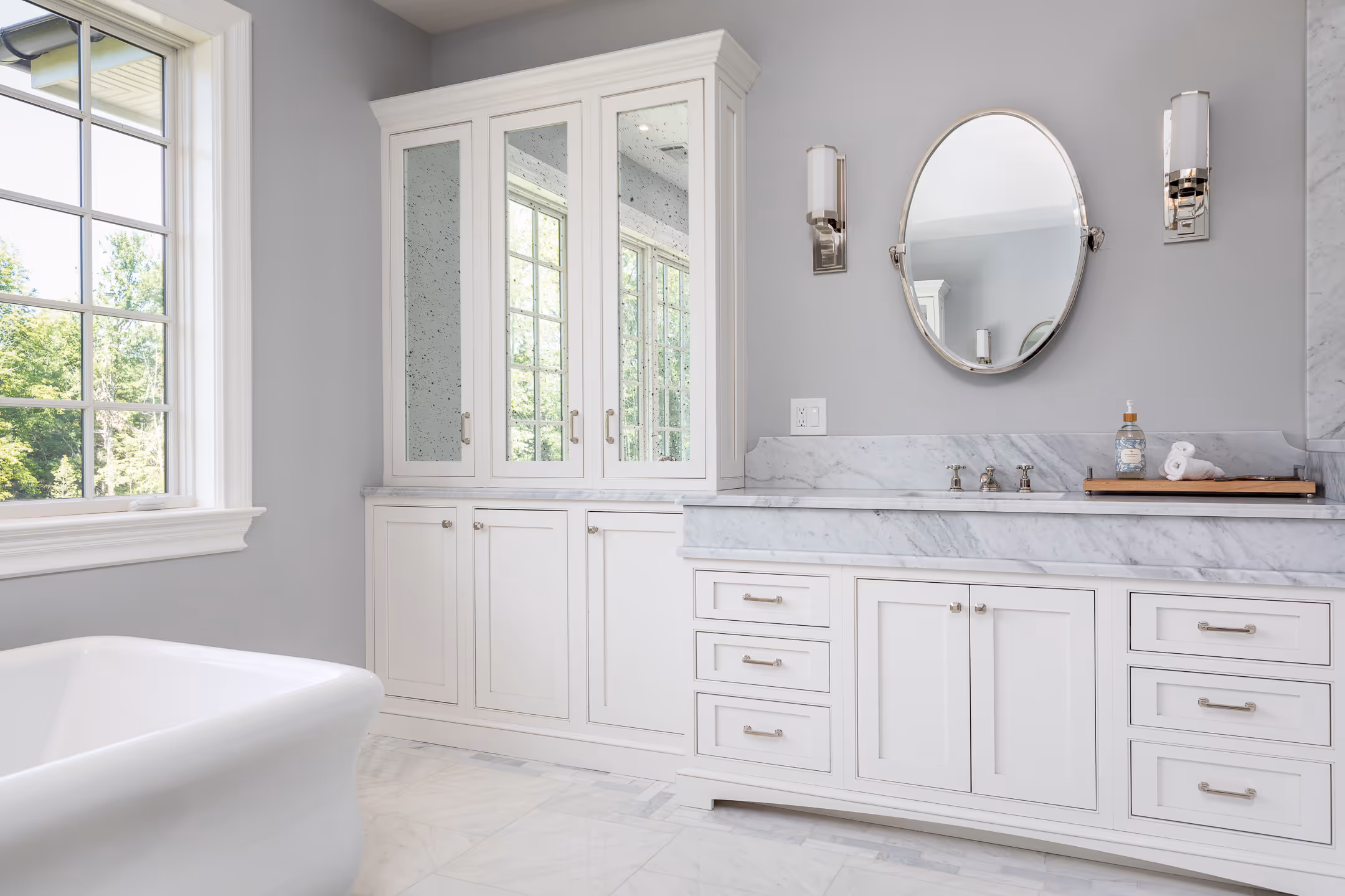 A stunning white redesigned bathroom with the daylight from the window highlighting the bathtub.