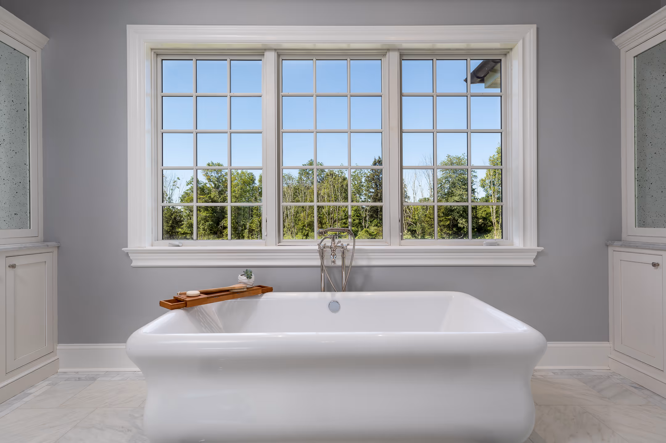 An interior design image of a bath tub with a beautiful window in the background.