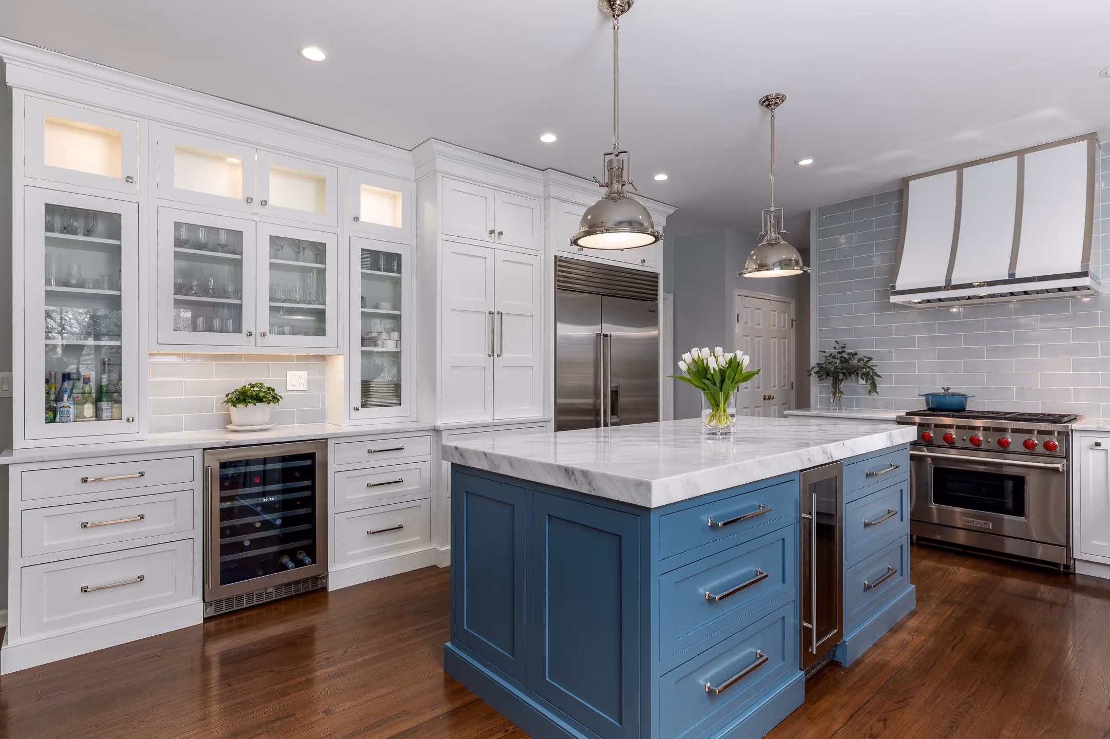 A real estate image of a beautiful kitchen with white cabinets and a matching blue island.