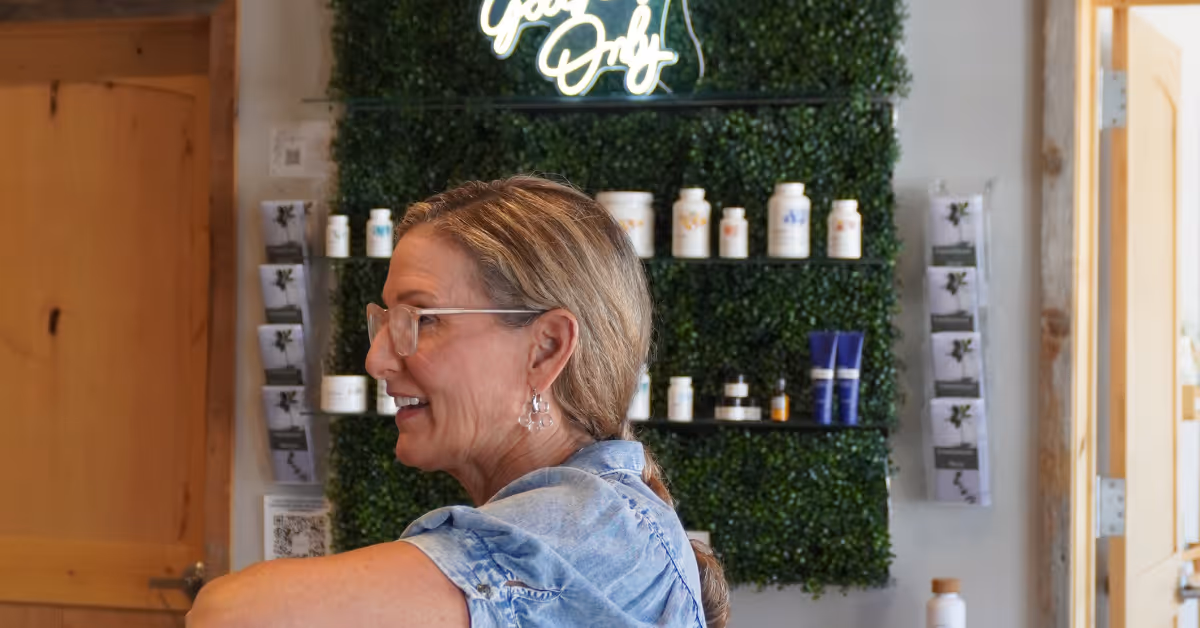 Patient smiling while speaking with staff inside Elite Wellness Chiropractic reception area, with wellness products displayed in the background.