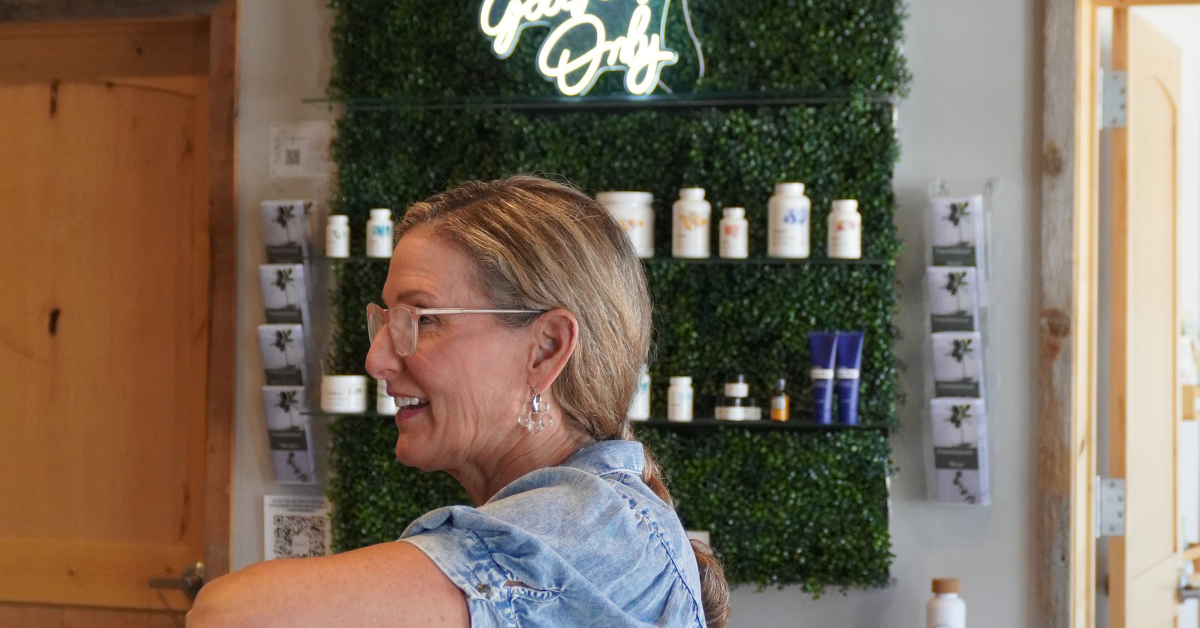 Patient smiling while speaking with staff inside Elite Wellness Chiropractic reception area, with wellness products displayed in the background.