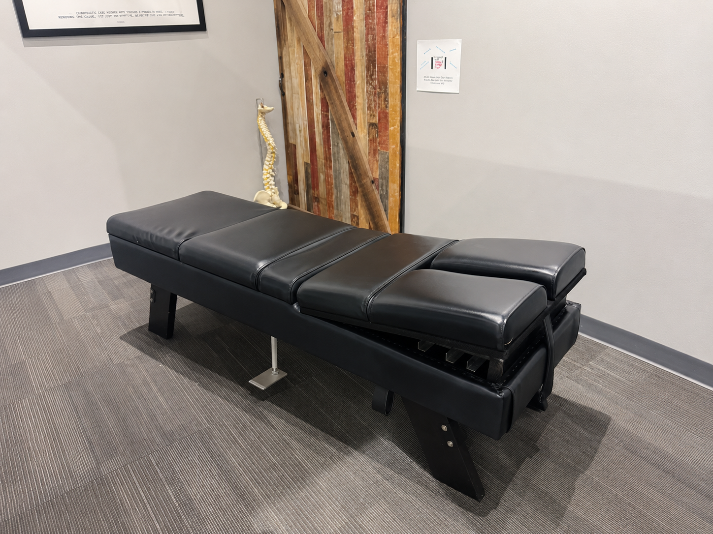 Treatment room featuring a chiropractic table used for spinal assessments and corrective care.