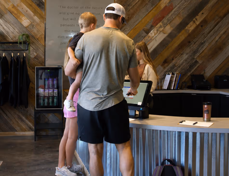 Family checking in at the front desk of Elite Wellness Chiropractic before an appointment in Bee Cave, Texas.