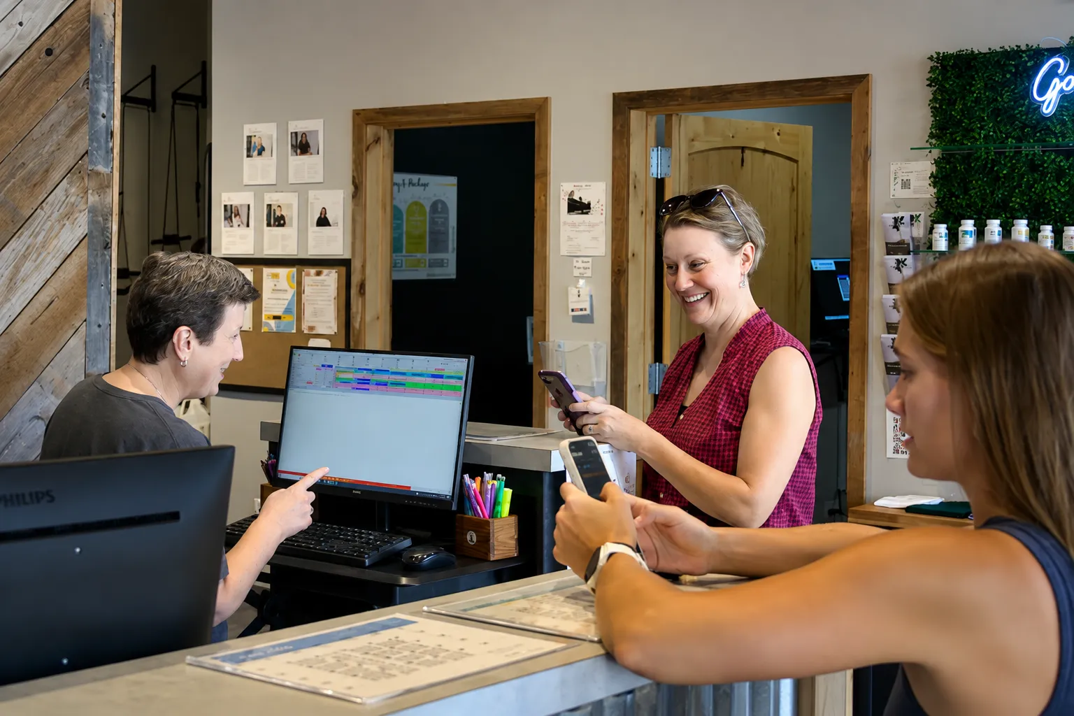 Elite Wellness Chiropractic team member speaking with patients at the front desk of the Bee Cave clinic.