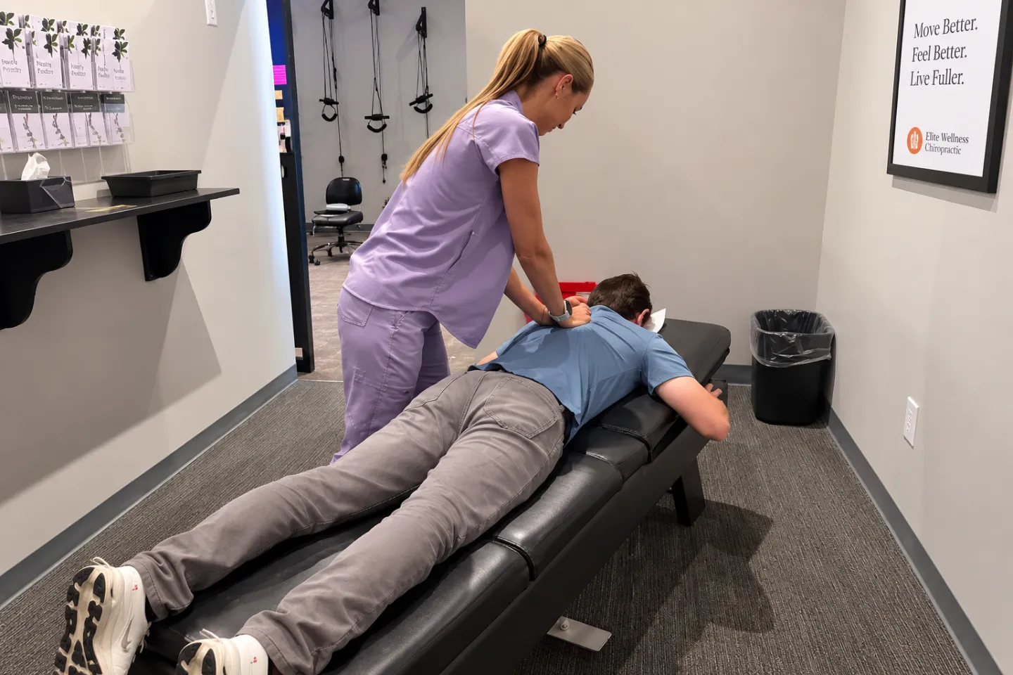 Dr. Mikala Hiben performs a chiropractic adjustment on a male patient lying face down on a treatment table in a modern clinic.