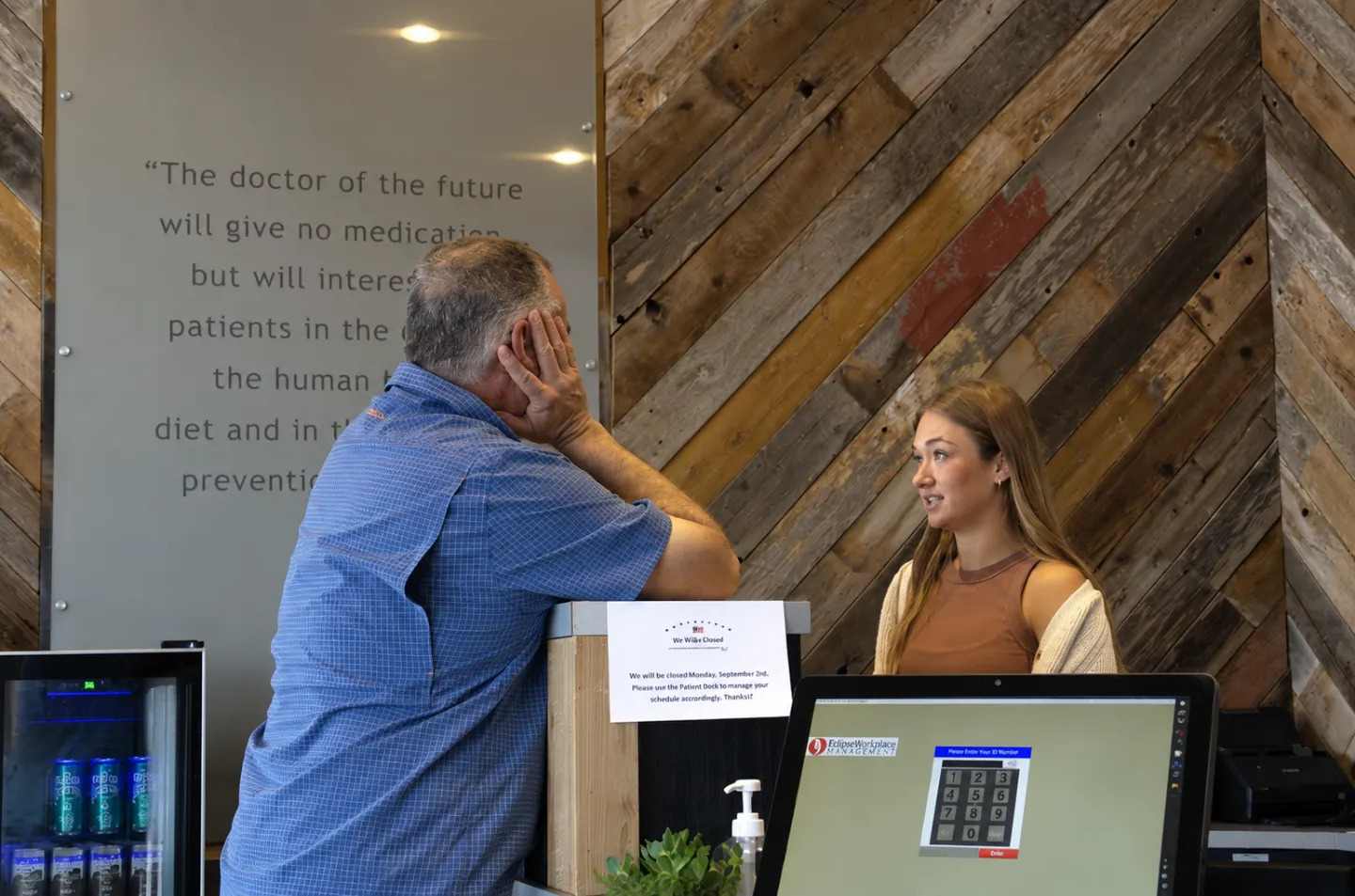 Patient speaking with a clinic team member at the reception desk of a chiropractic office. 