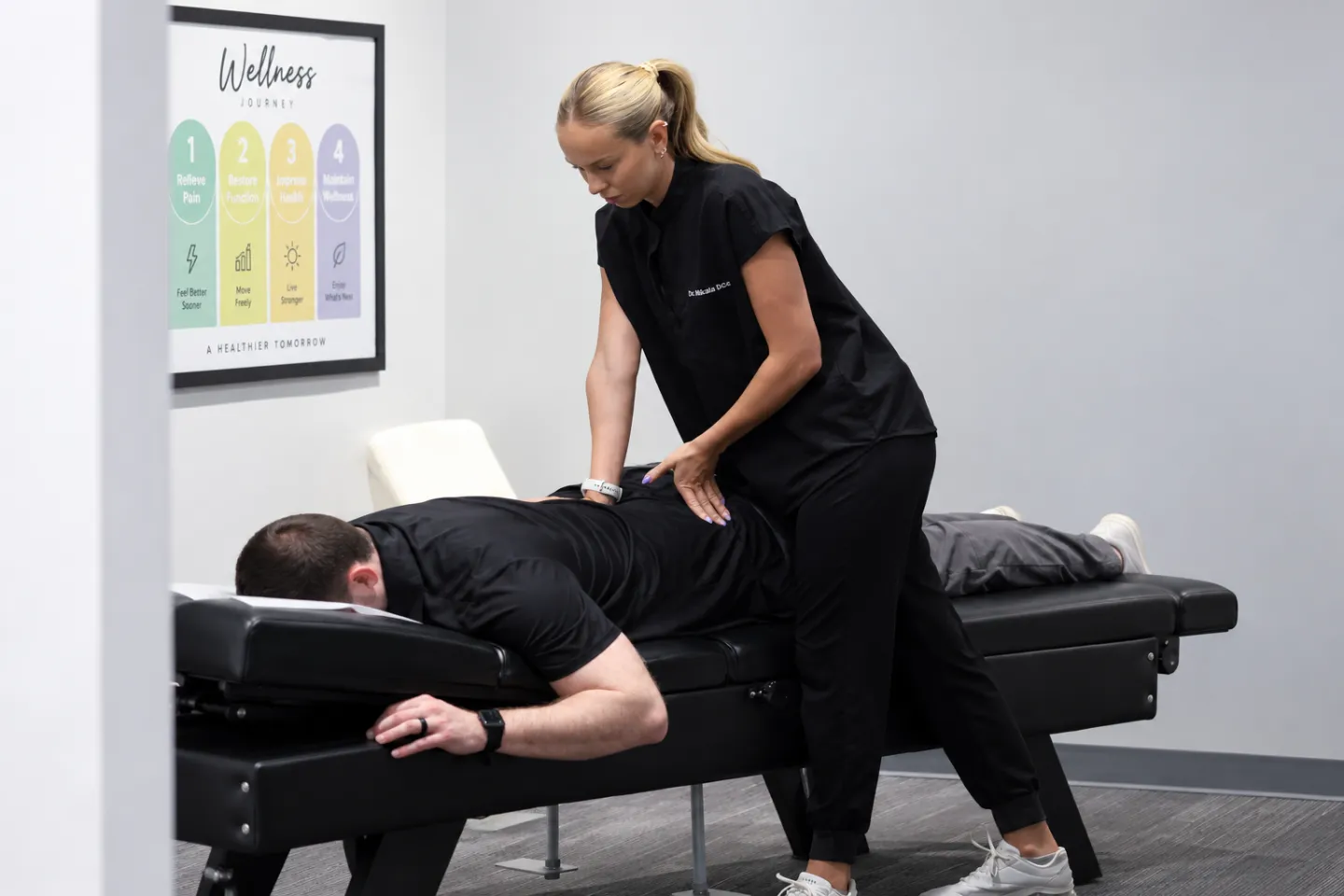 Dr. Mikala Hiben performing a spinal adjustment on a patient lying face down on a chiropractic treatment table. 