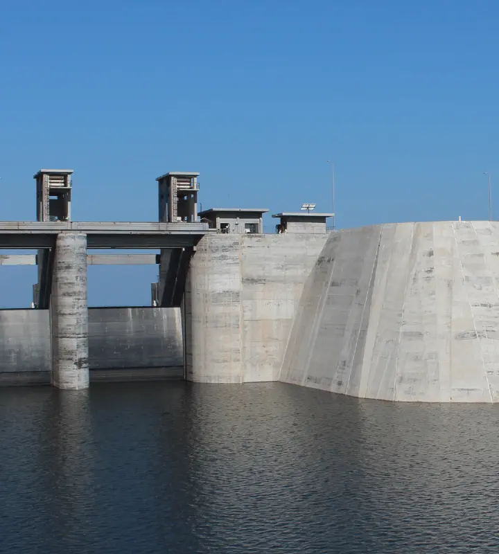 Estructura de una presa de concreto bajo un cielo azul claro sobre un cuerpo de agua.