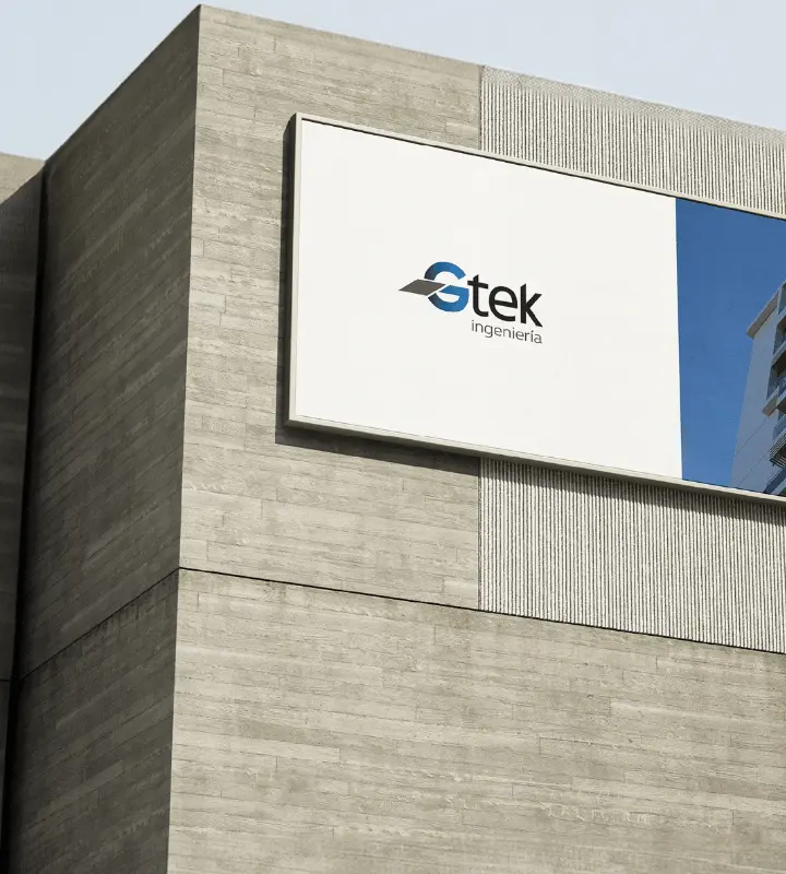 Edificio de concreto con cartel que muestra el logo de Stek ingeniería y reflejo de otra estructura.