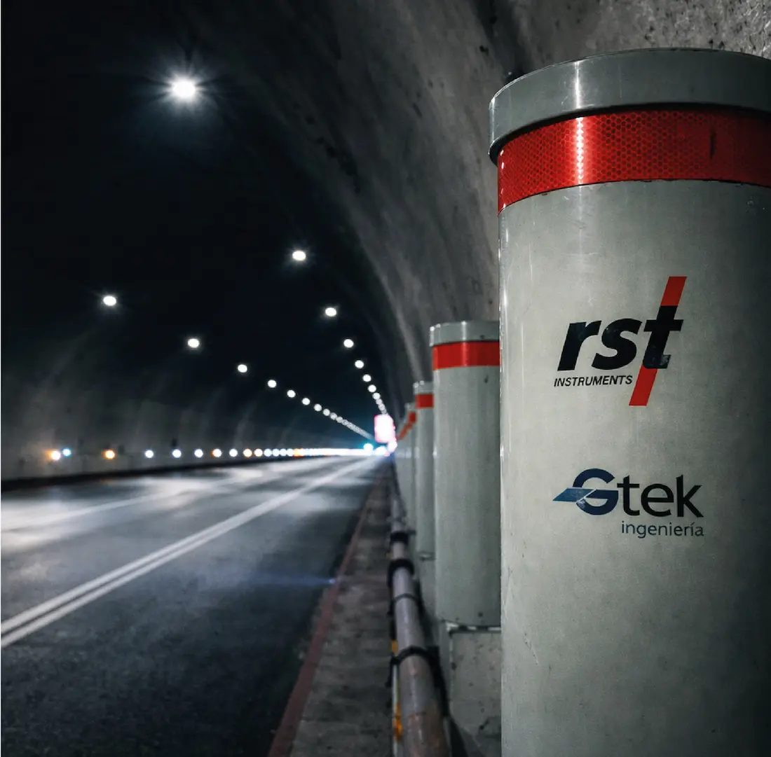 Postes grises con franjas rojas y logos RST Instruments y Gtek Ingeniería en un túnel iluminado