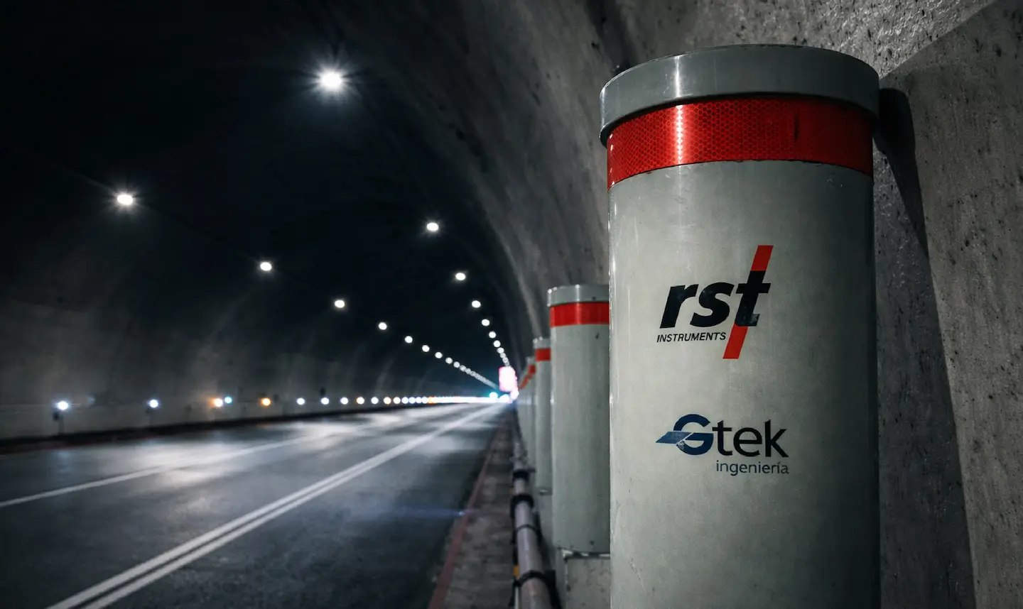Columnas grises con logotipos de rst instruments y stek ingeniería en un túnel iluminado.