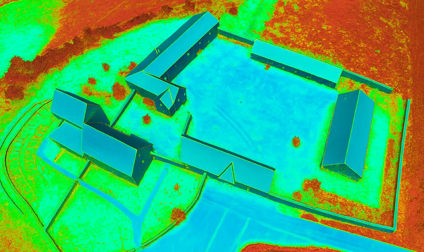 Vista aérea térmica de un conjunto de edificios rectangulares dentro de un terreno cercado.