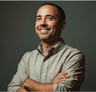 Smiling professional in light shirt with crossed arms against dark background