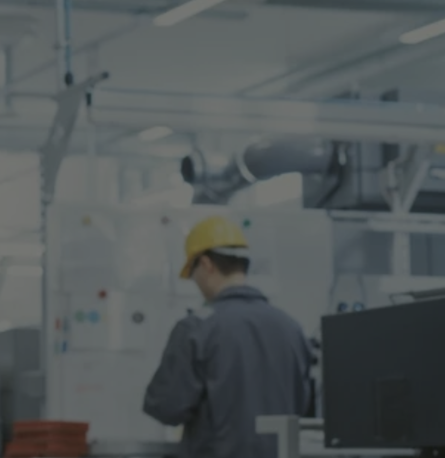 Worker in yellow hard hat standing in industrial facility with machinery