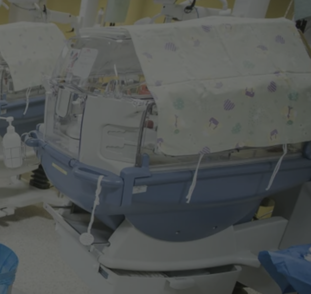 Infant incubator with blue base and decorated cover in hospital setting