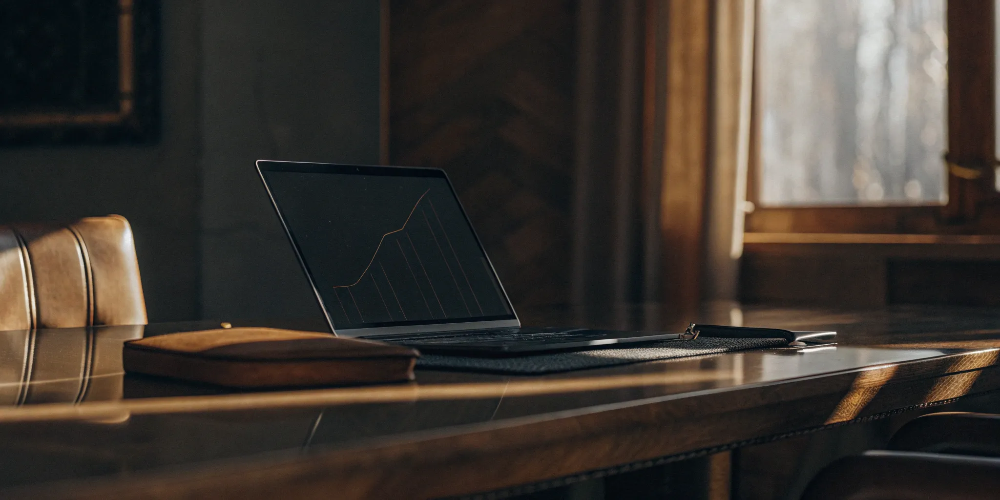 A laptop on a desk showing a graph for a business compensation plan.