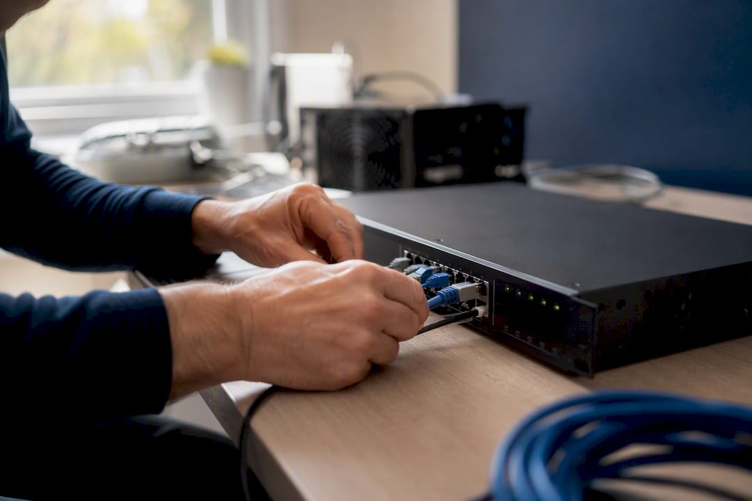Hands connecting cable to networking hardware