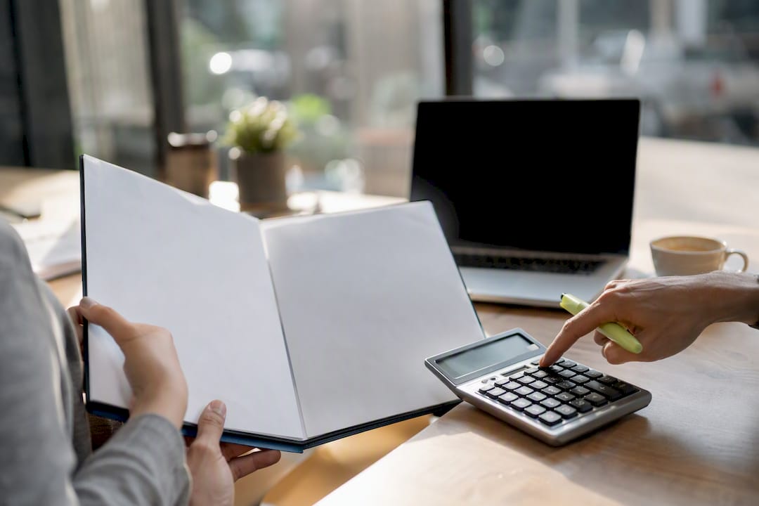 Hands auditing billing with calculator and binder