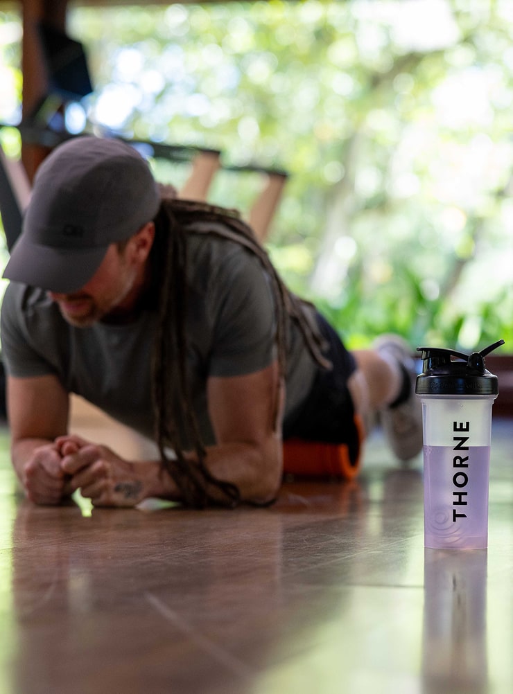Trainer Games contestant Dan Holguin holding a plank in the gym with a Thorne shaker bottle in the foreground