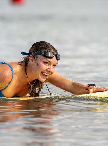 A female competitor paddling on a surfboard wearing a Samsung Galaxy Watch Ultra