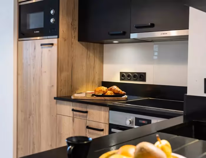 Cuisine moderne d’un appartement de vacances à Combloux, Haute-Savoie, avec croissants frais et vue sur les Alpes françaises.