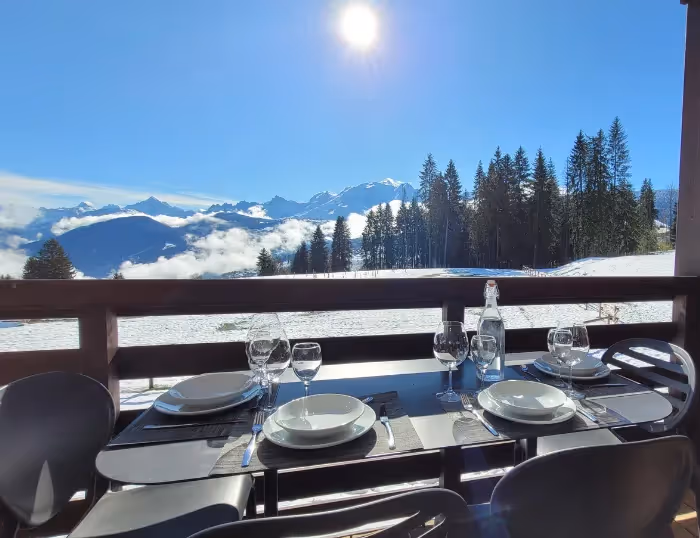 Repas en terrasse dans un appartement de vacances à Combloux, Haute-Savoie, face à la neige et au Mont-Blanc, proche station de ski.