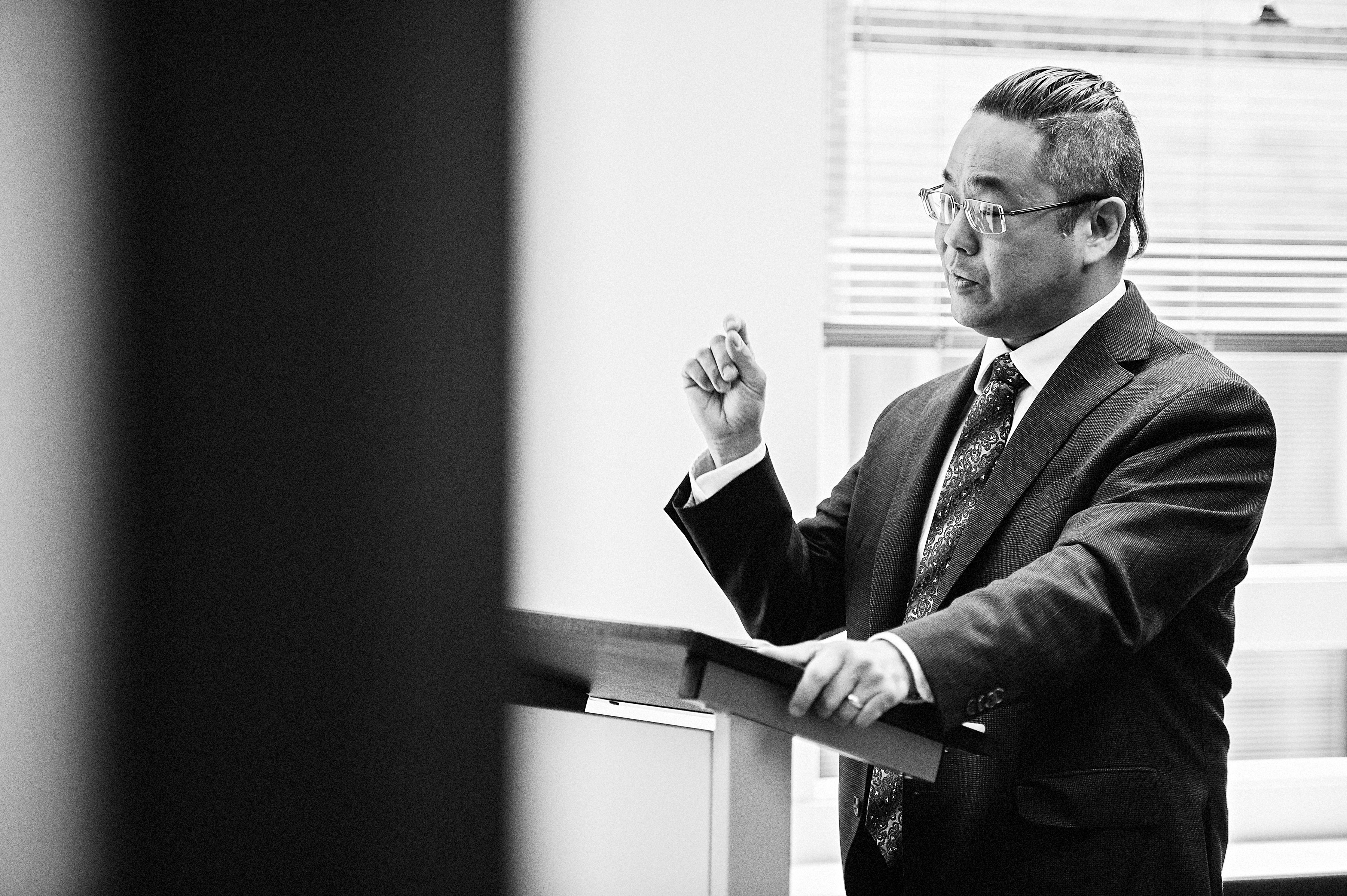 Man standing at a desk and giving a speech.