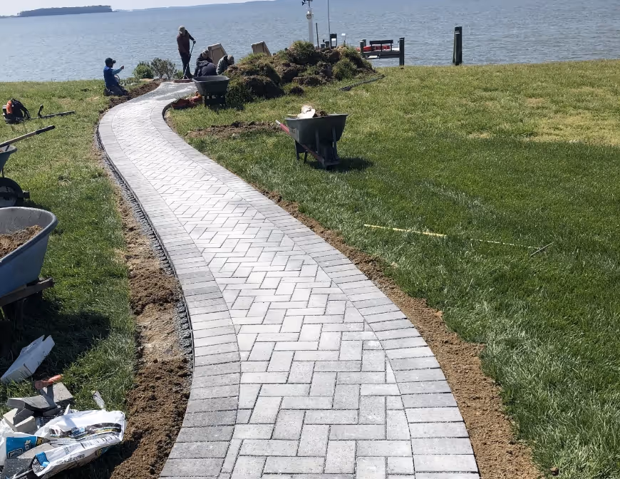 Image of a paver-stone path being constructed leading to a dock on the water