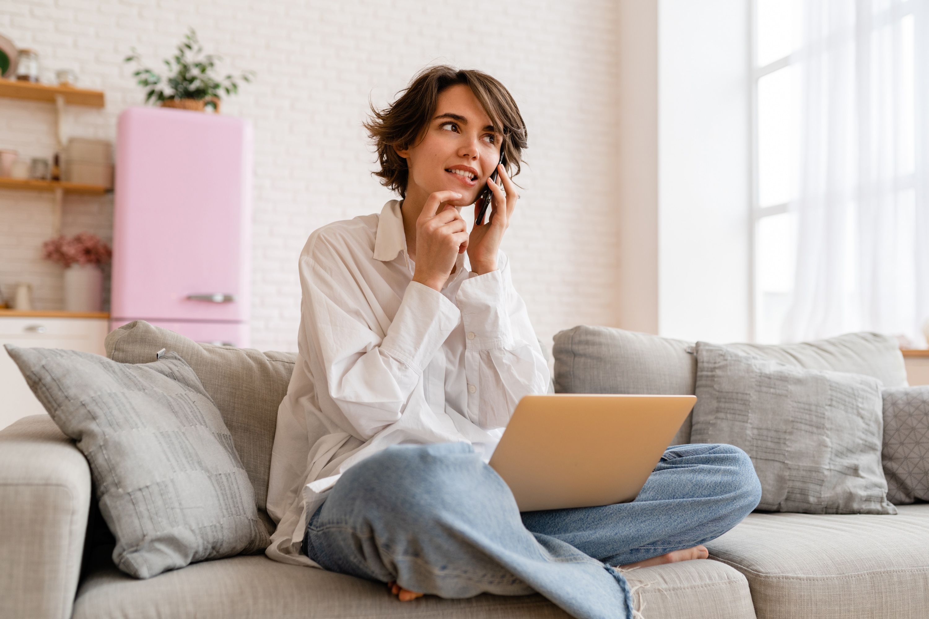 A resident relaxing on a couch with a laptop and phone at The Rook apartments in Orlando, highlighting the community's student-friendly living and remote-work spaces near UCF.