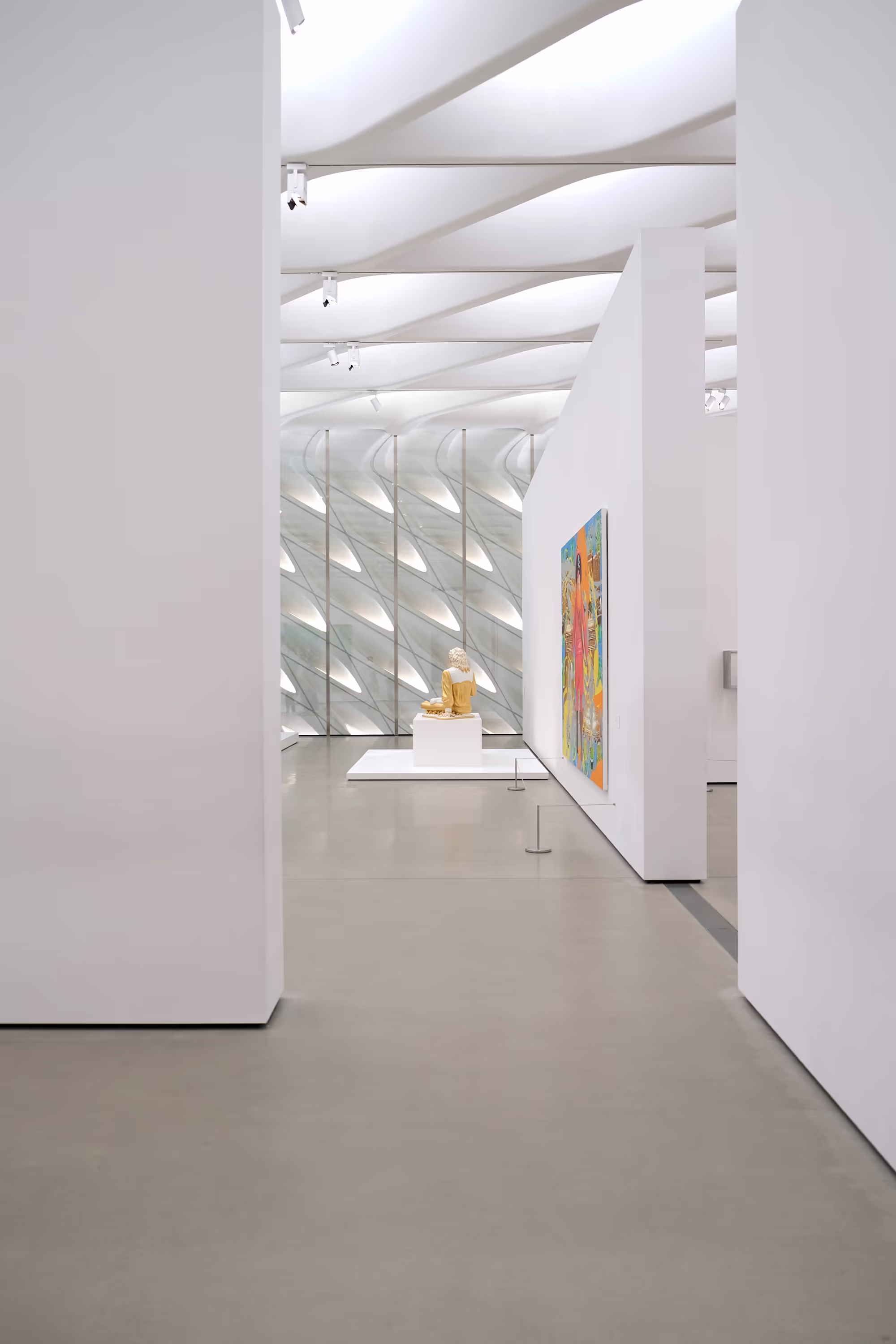 A modern art gallery with a sculpture on display and a colorful painting on the wall