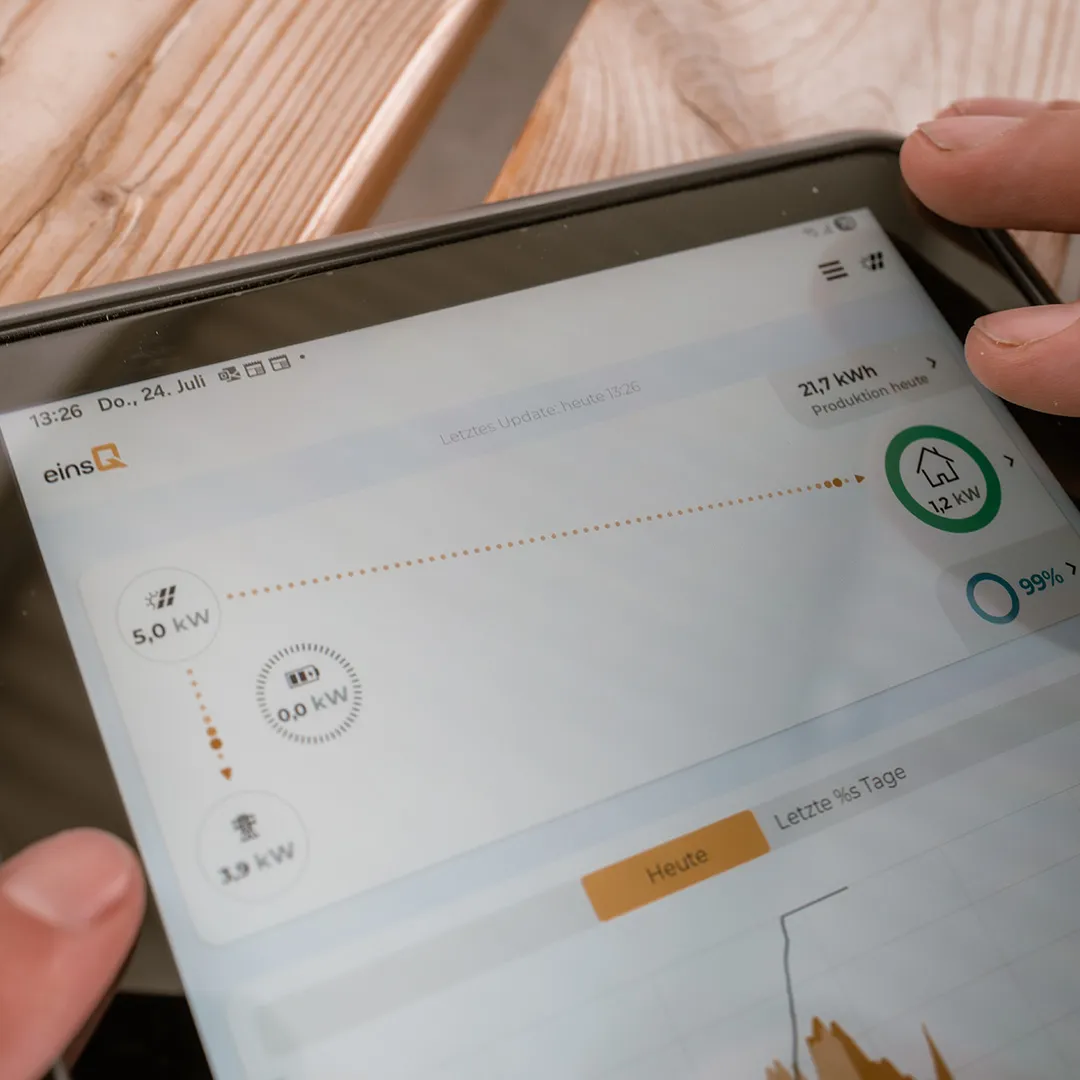 Eine Person interagiert mit einem Tablet, auf dem Daten zur Energieerzeugung angezeigt werden, darunter aktuelle und historische Stromverbrauchsdaten.
