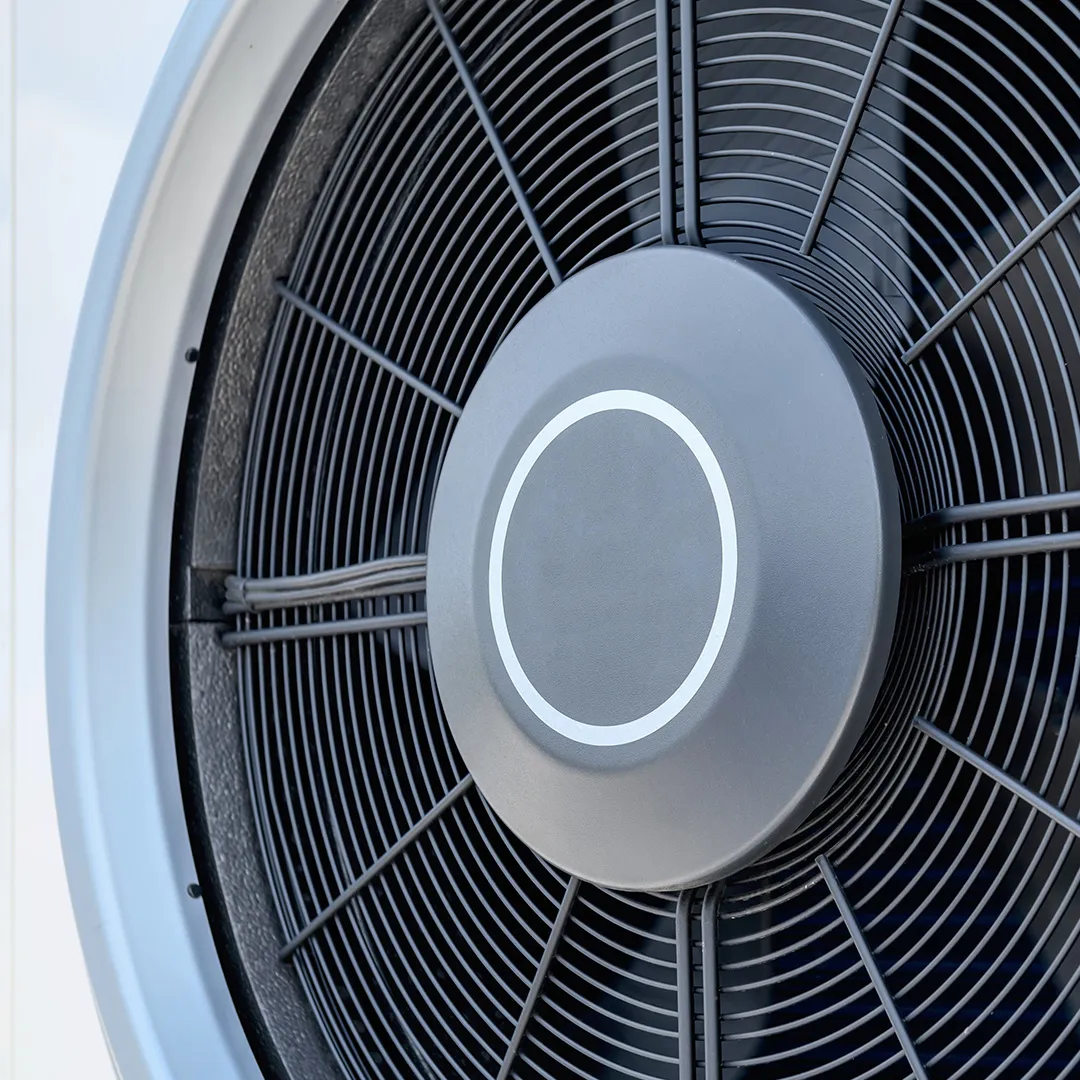 Nahaufnahme eines Ventilators einer Wärmepumpe mit kreisförmigen Flügeln und einer zentralen Nabe mit einem Lichtring.