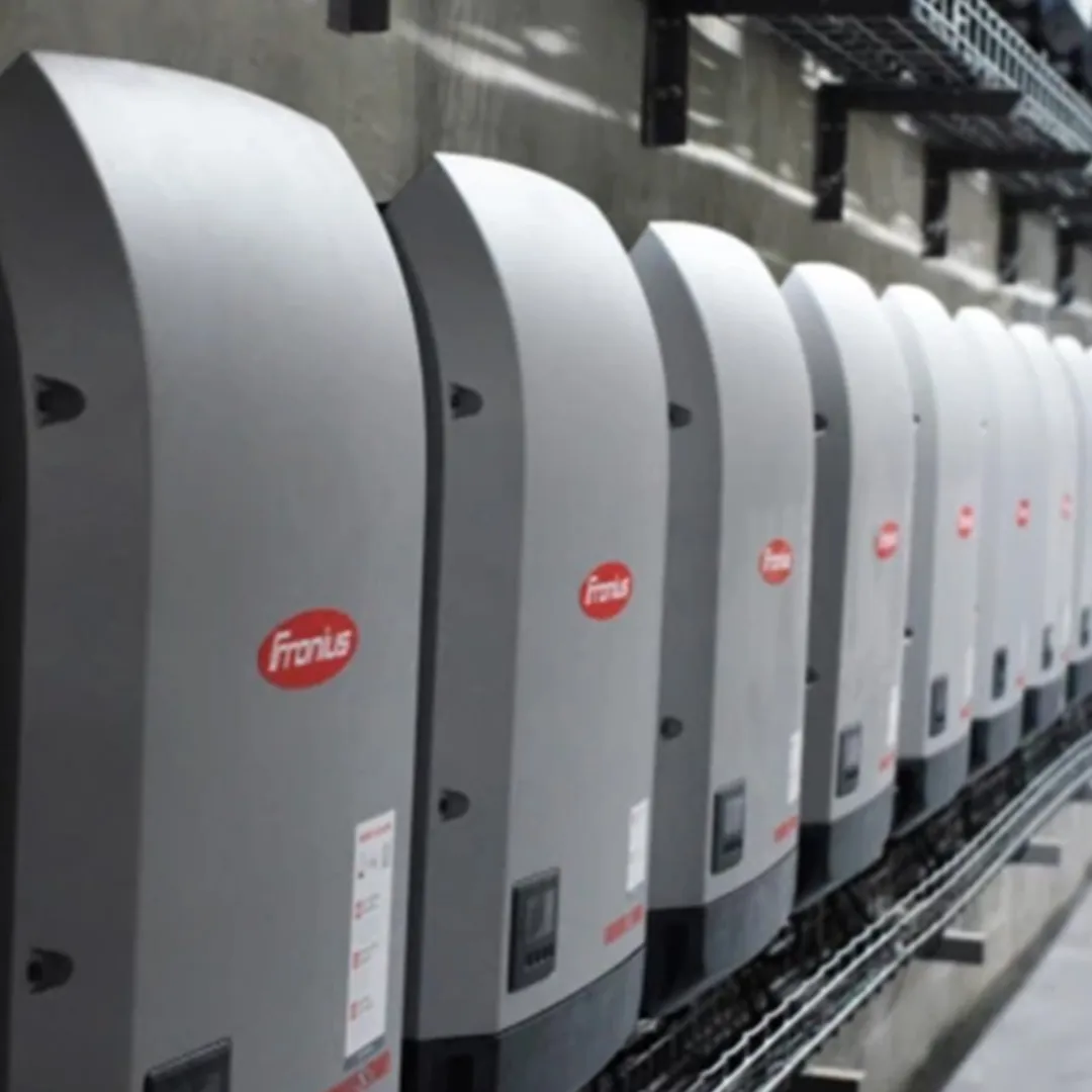 Eine Reihe von Fronius-Solarwechselrichtern, die an einer Wand montiert sind und eine saubere und übersichtliche Installation für erneuerbare Energiesysteme zeigen.