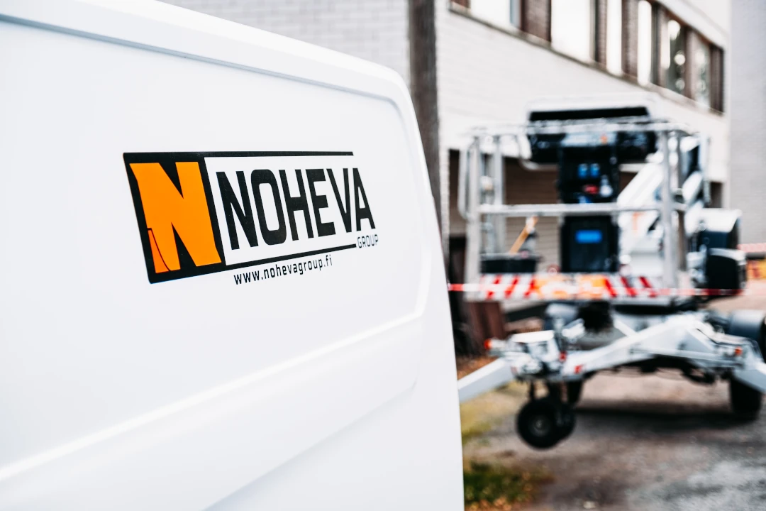 Nohevan auto ja nosturi kerrostalon pihassa
