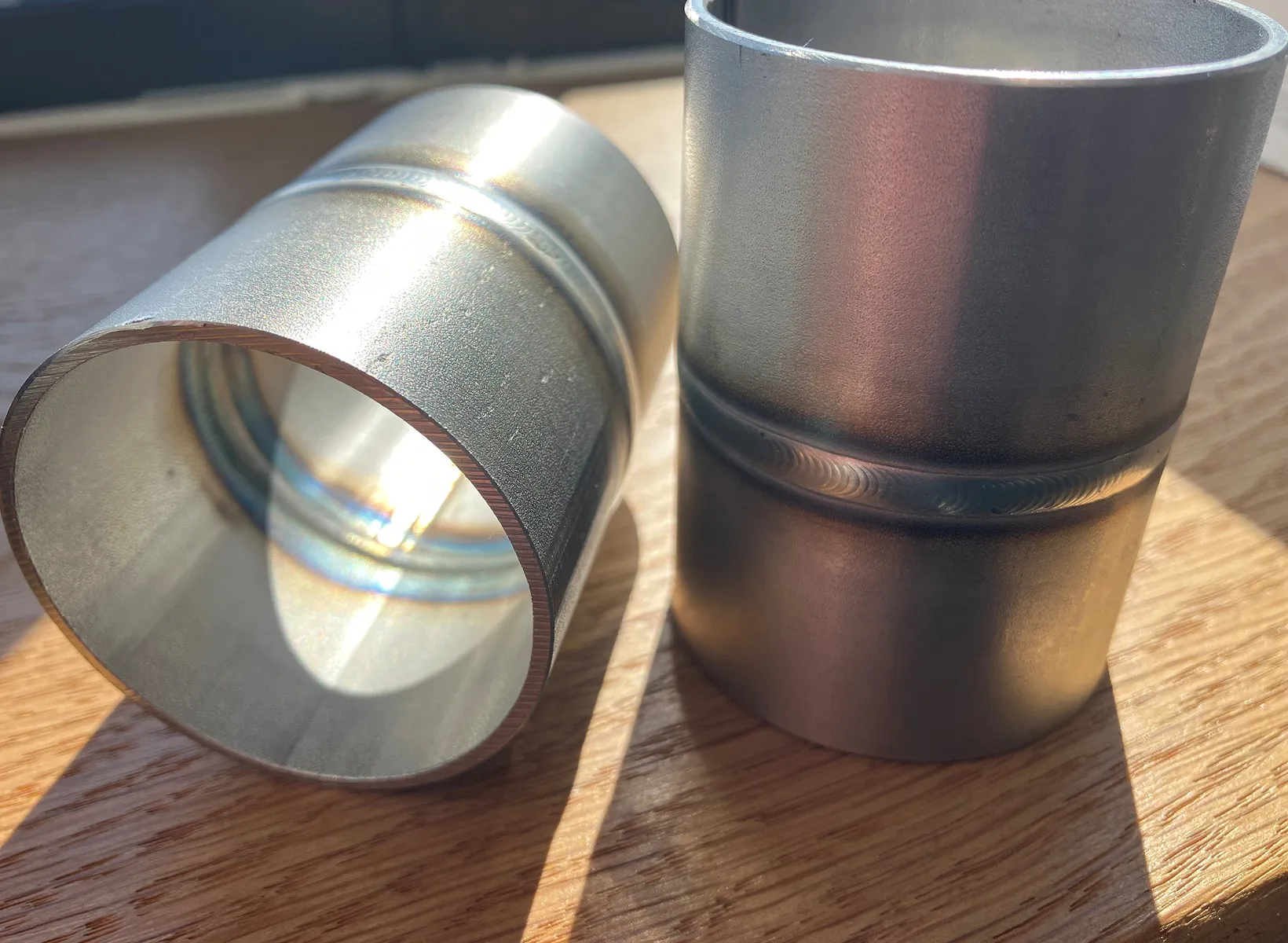 A metal cup sitting on top of a wooden table.