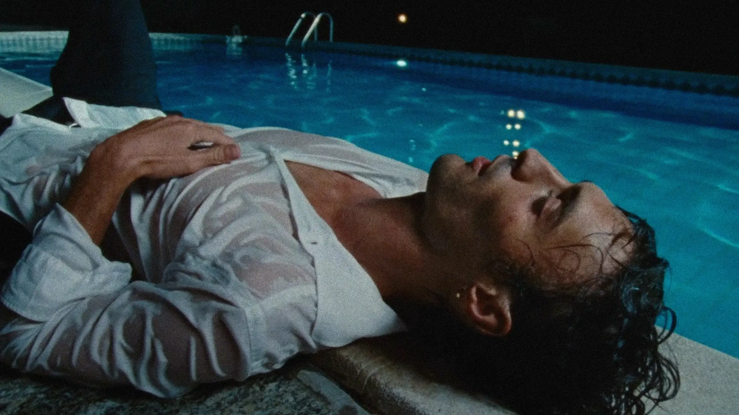 Male model lying by a lit pool at night in a wet white shirt — MAXIMILIAN F/W campaign film by Studio ONOM.