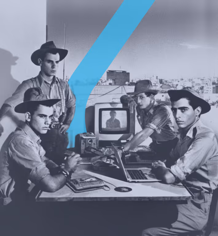 קבוצת גברים צעירים בלבוש חלוצי יושבים סביב שולחן על גג עירוני, עובדים עם מחשב נייד, מסך טלוויזיה ישן ומכשור טכנולוגי נוסף; התמונה בשחור-לבן עם אלמנט עיצובי טורקיז בצורת חץ החוצה את הסצנה.