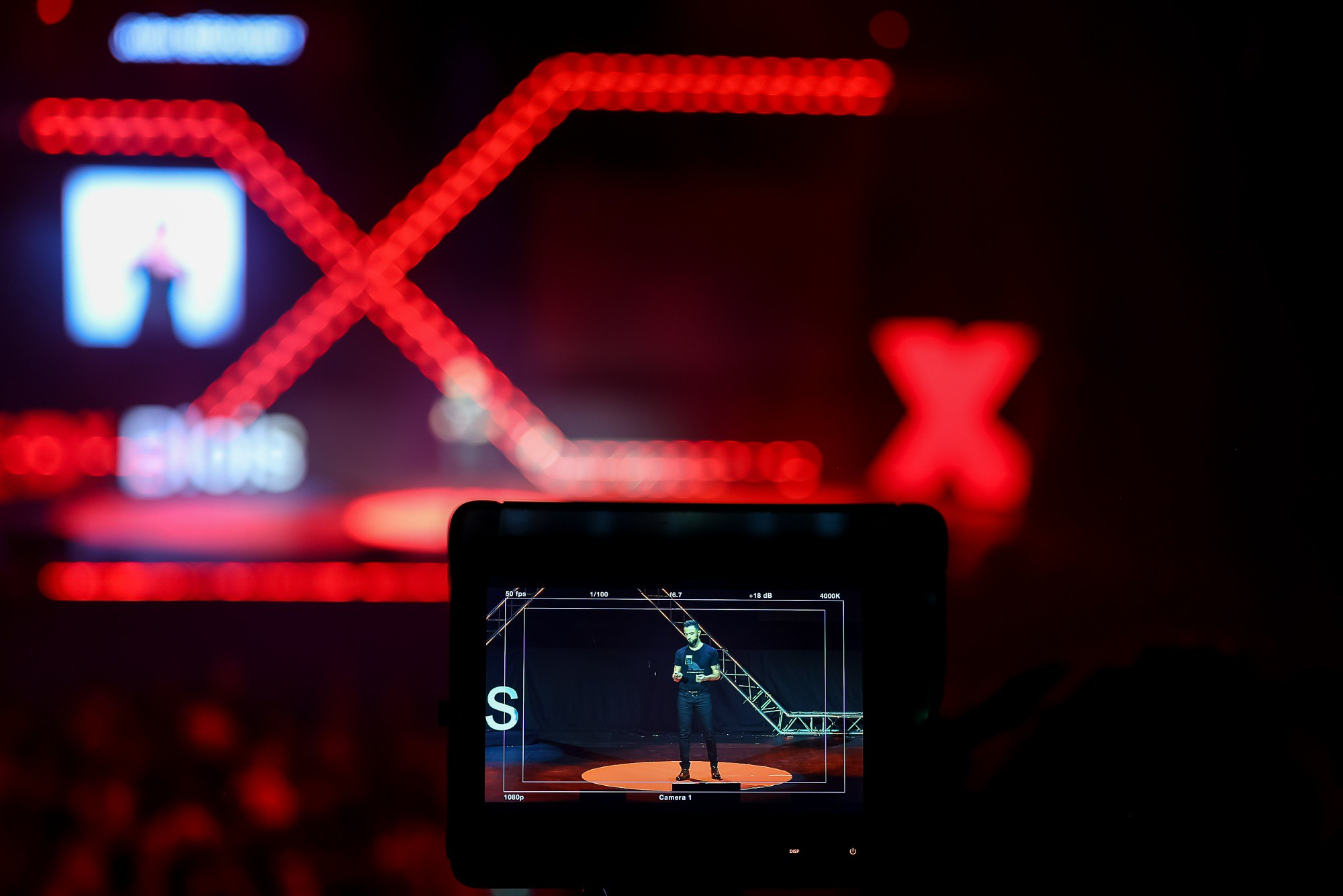 Scène TEDxBlois 2021 avec Julien Bédouret. La scène est floutée mais on la voit à travers l'écran numérique d'une caméra.