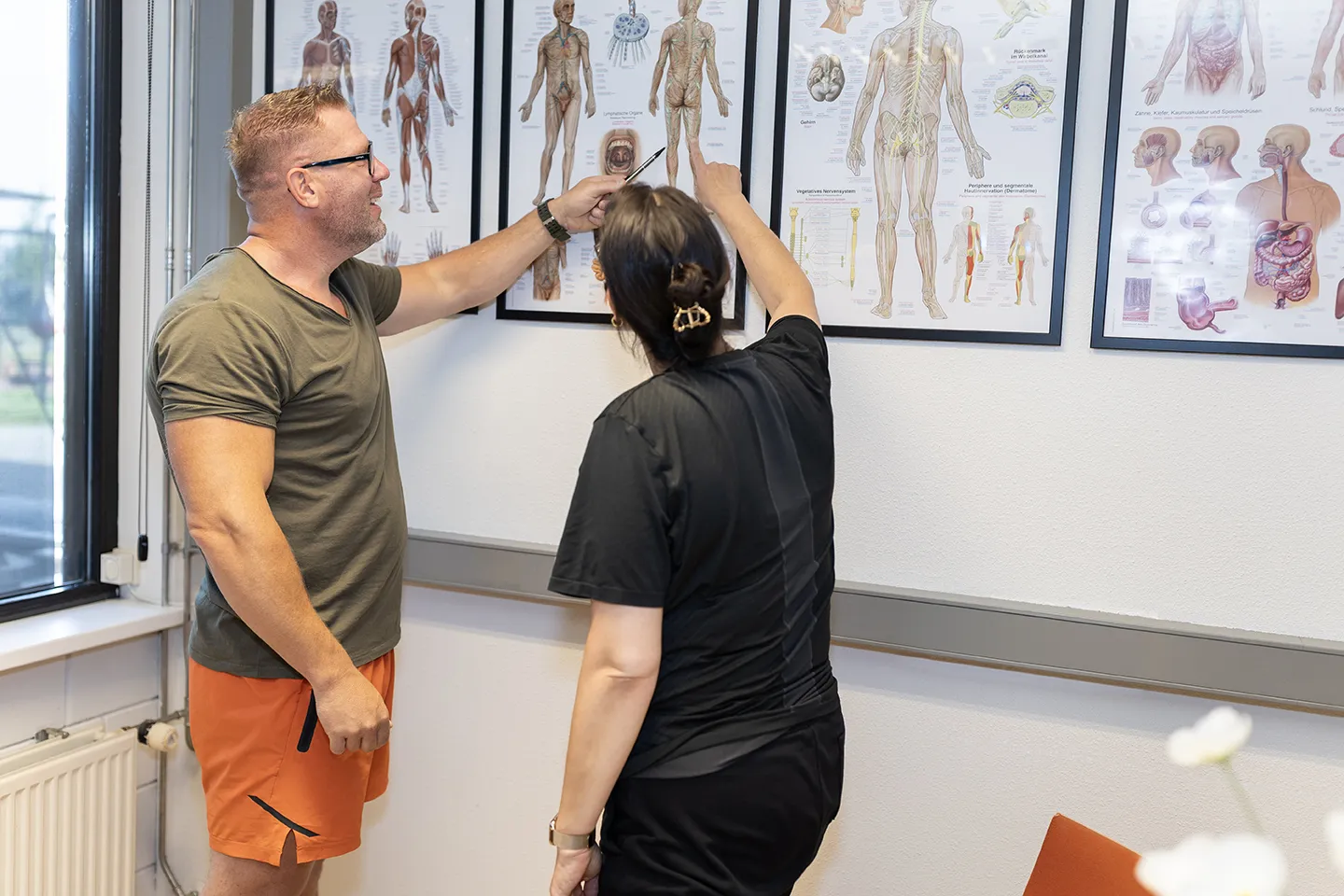 Benjamin die met een client wijst naar een anatomische tekening