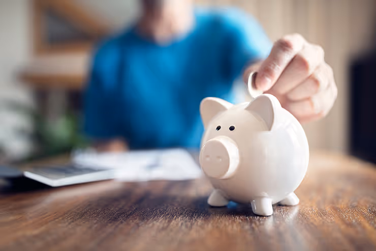 A person putting a coin into a piggy bank.
