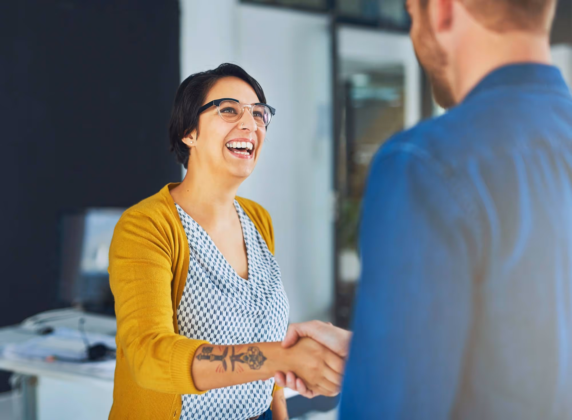 A woman shakes a man's hand in an office setting.