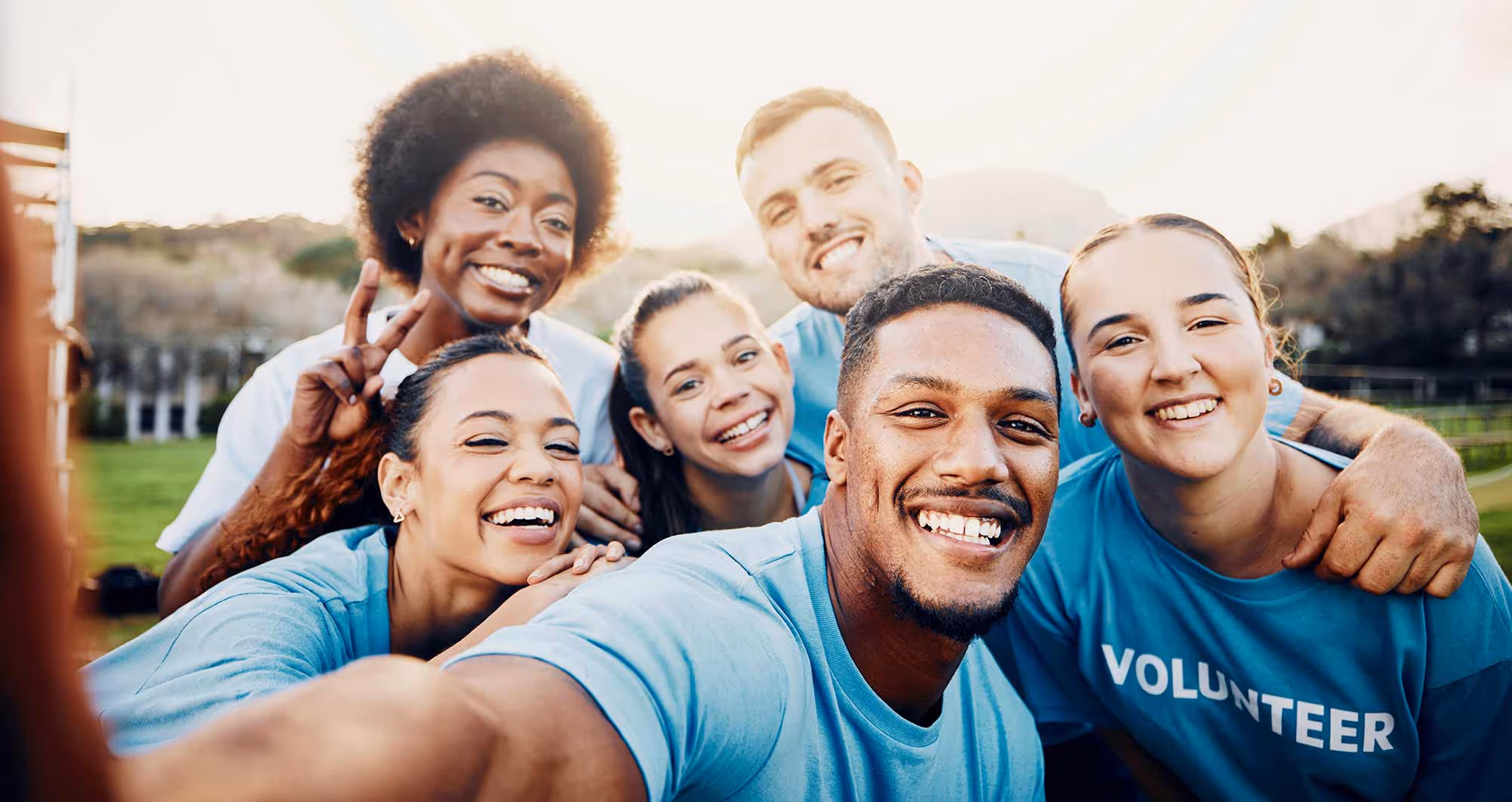 A group of volunteers huddle together and smile for a selfie.