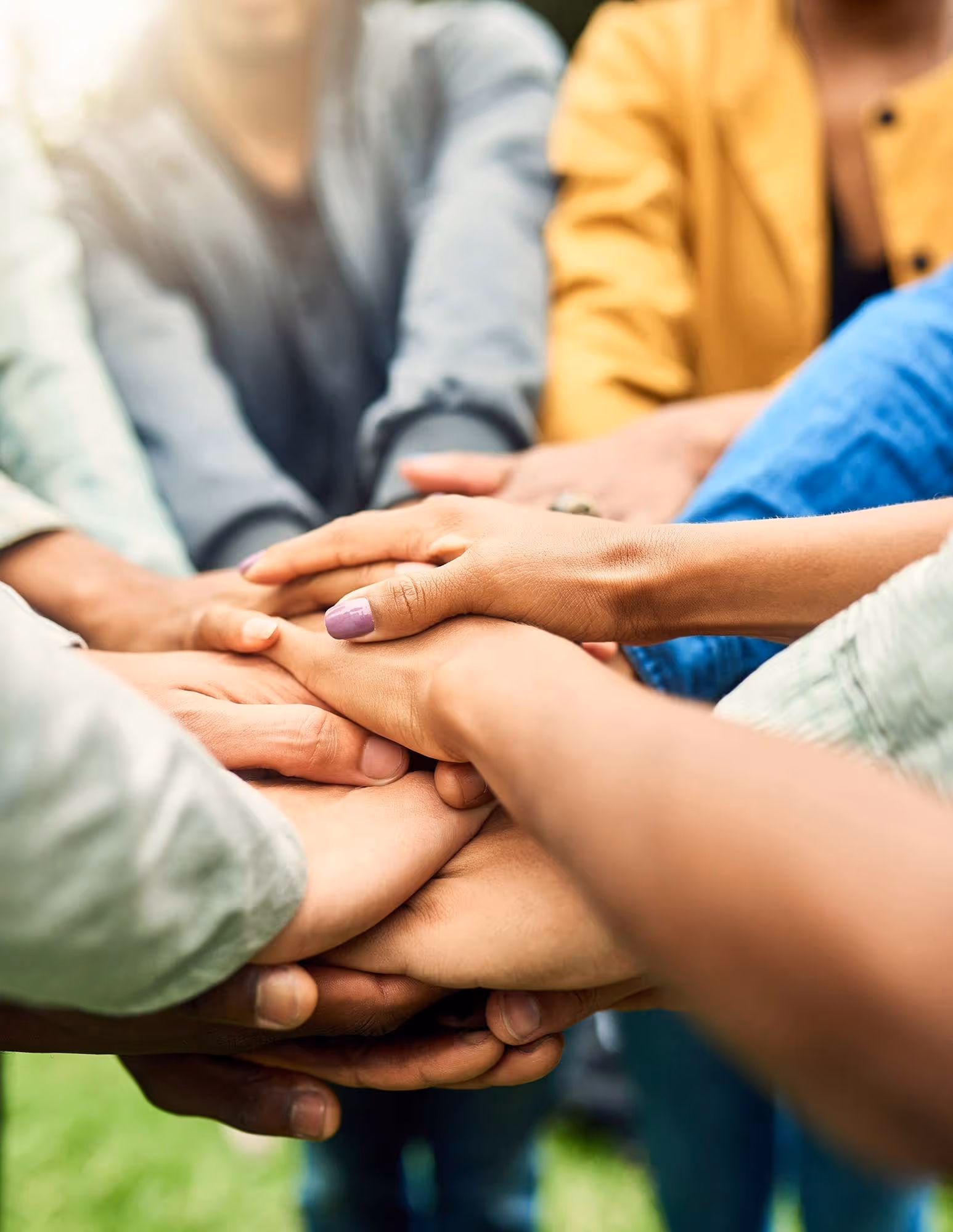 Team of hands together in the middle of a circle.
