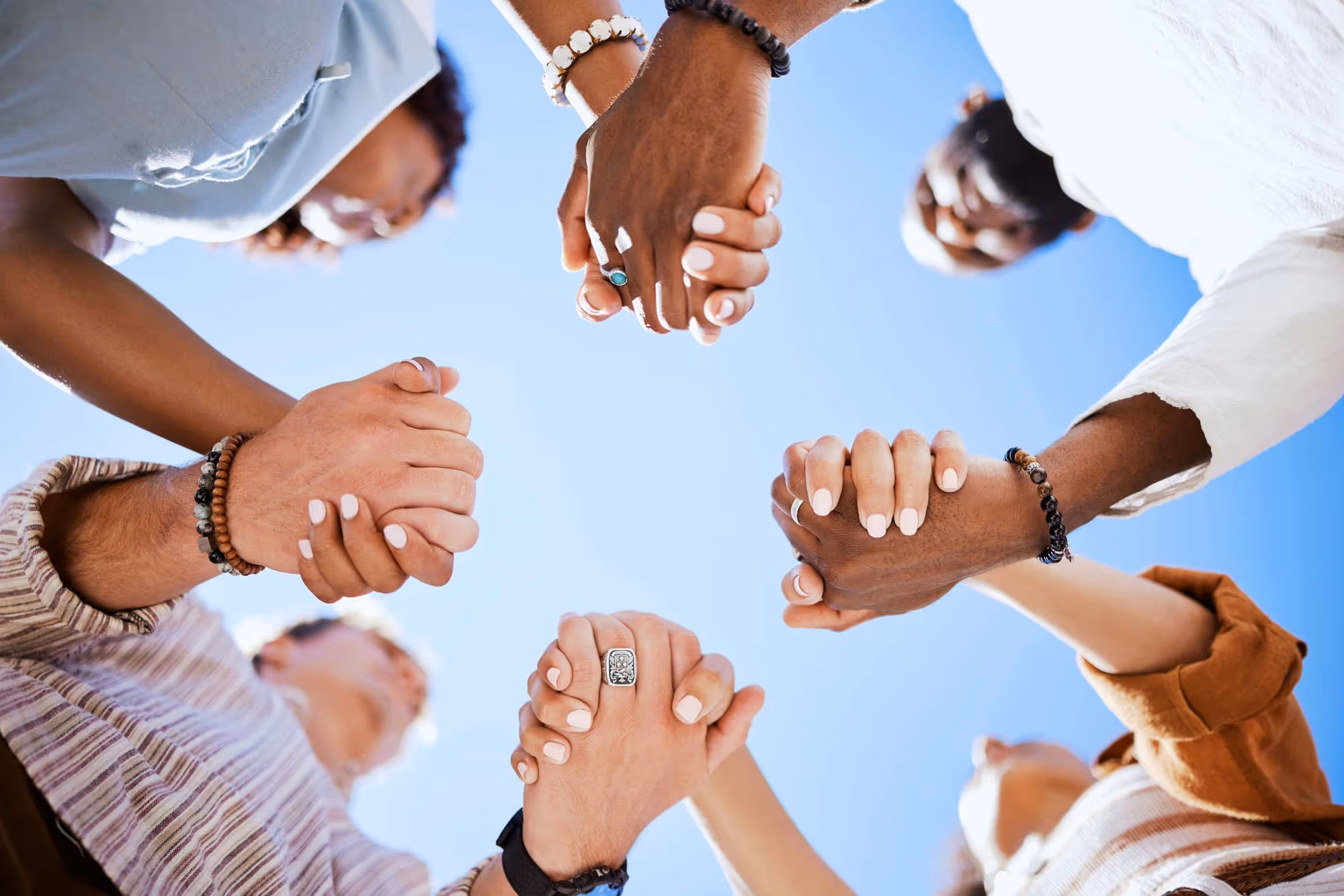 Group of people hold hands in a circle.