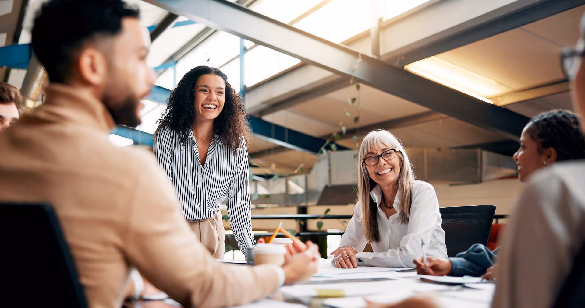 Group of people smile around a table in a brightly lit modern office.