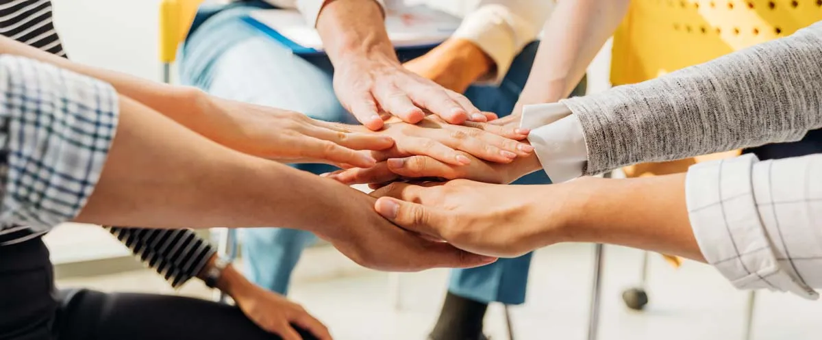 Group of people joining hands together in a show of unity and teamwork.