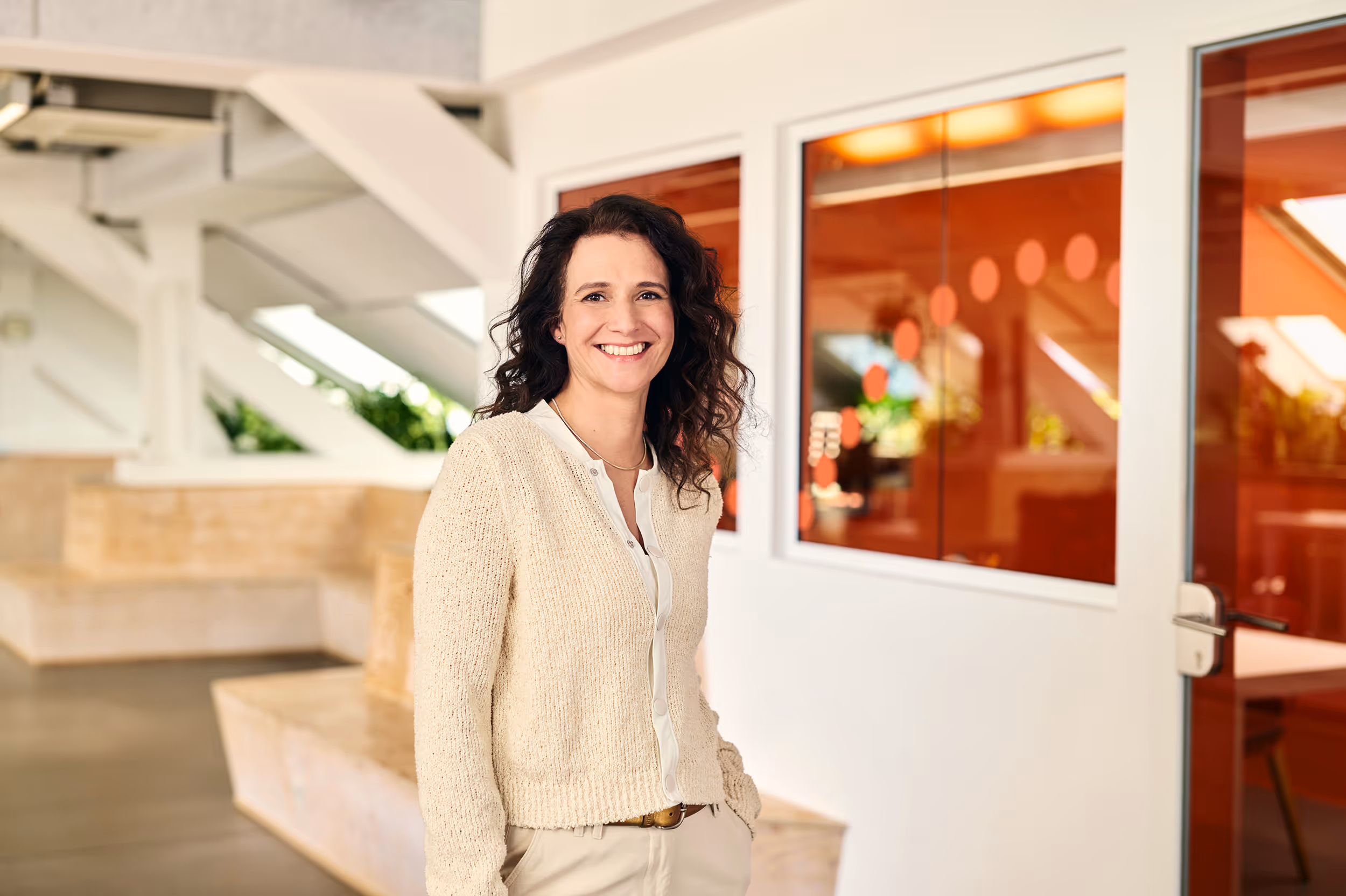 A lady standing in peach colored clothes smiling towards the camera