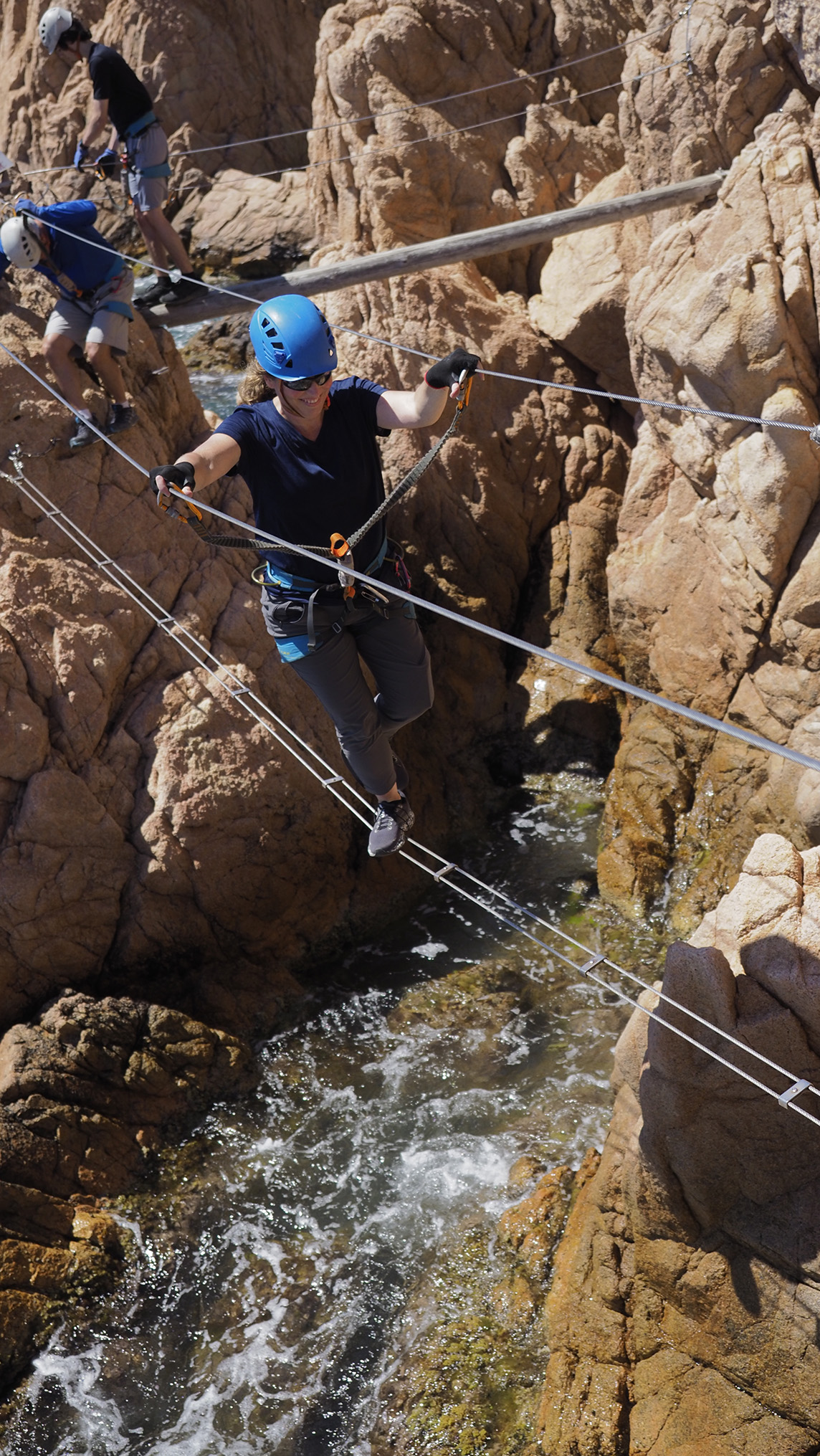 Person crossing a coastal rope bridge in safety gear—reflecting confidence, strength, and active living supported by Thriving Life Clinic in Bee Cave, TX.